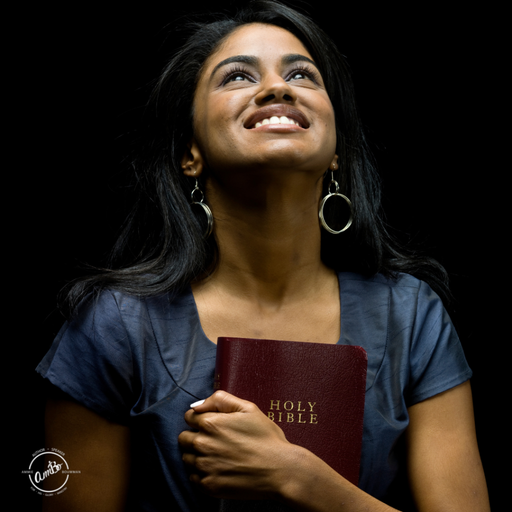 A woman holding a bible and looking up at the sky.