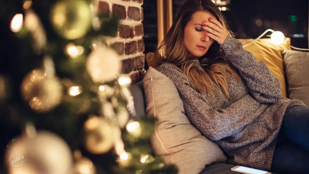 A woman sitting on the couch with her hand over her face.