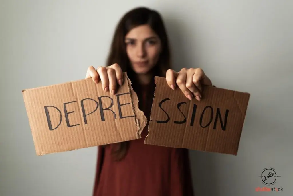 A woman holding two pieces of cardboard with the word depression written on them.