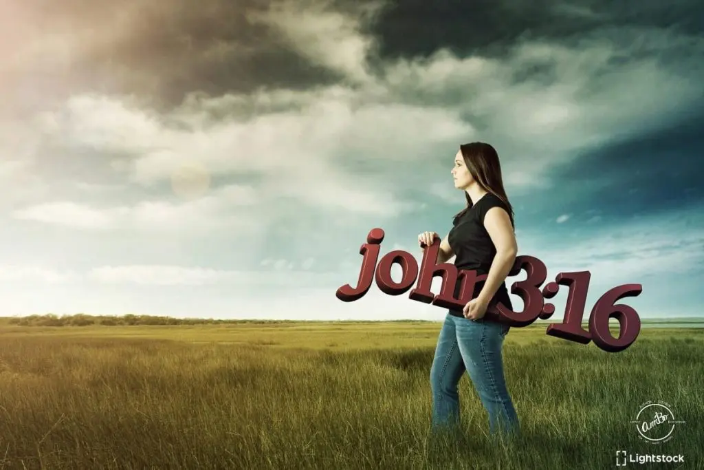 A woman holding a large sign in the middle of a field.