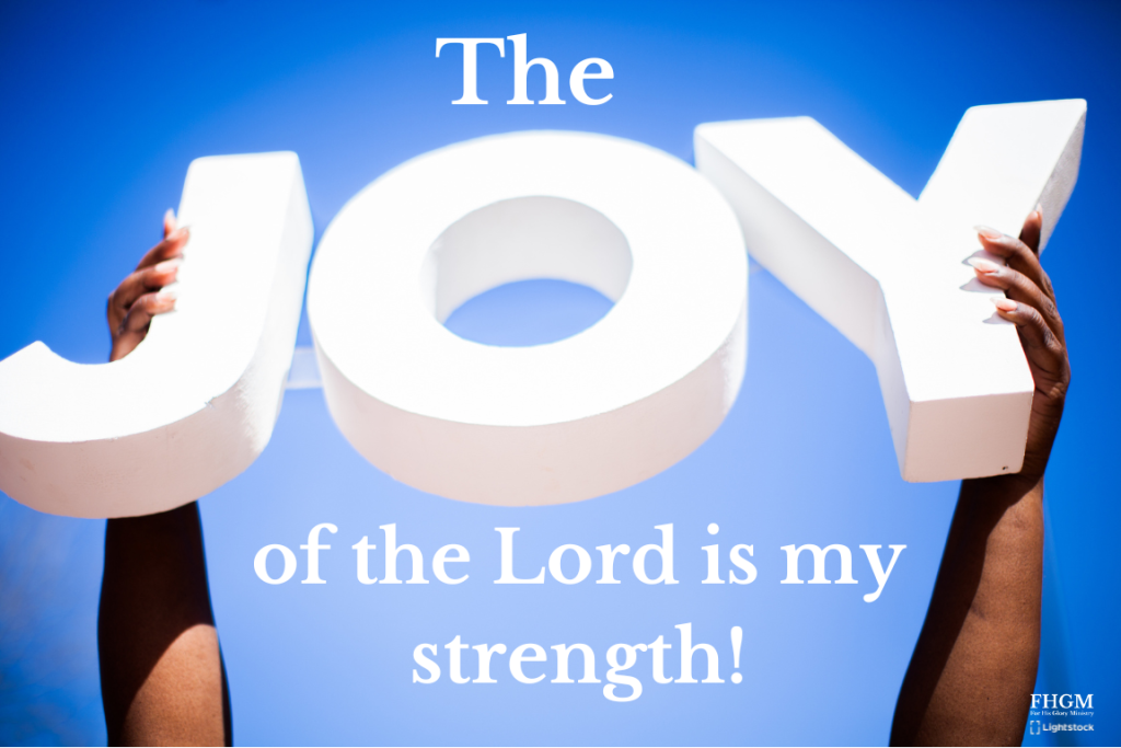 A person holding up the word joy in front of their face.