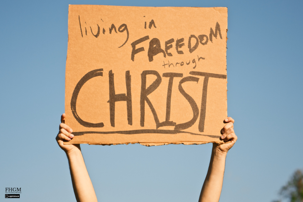 A person holding up a sign that says " living in freedom through christ ".