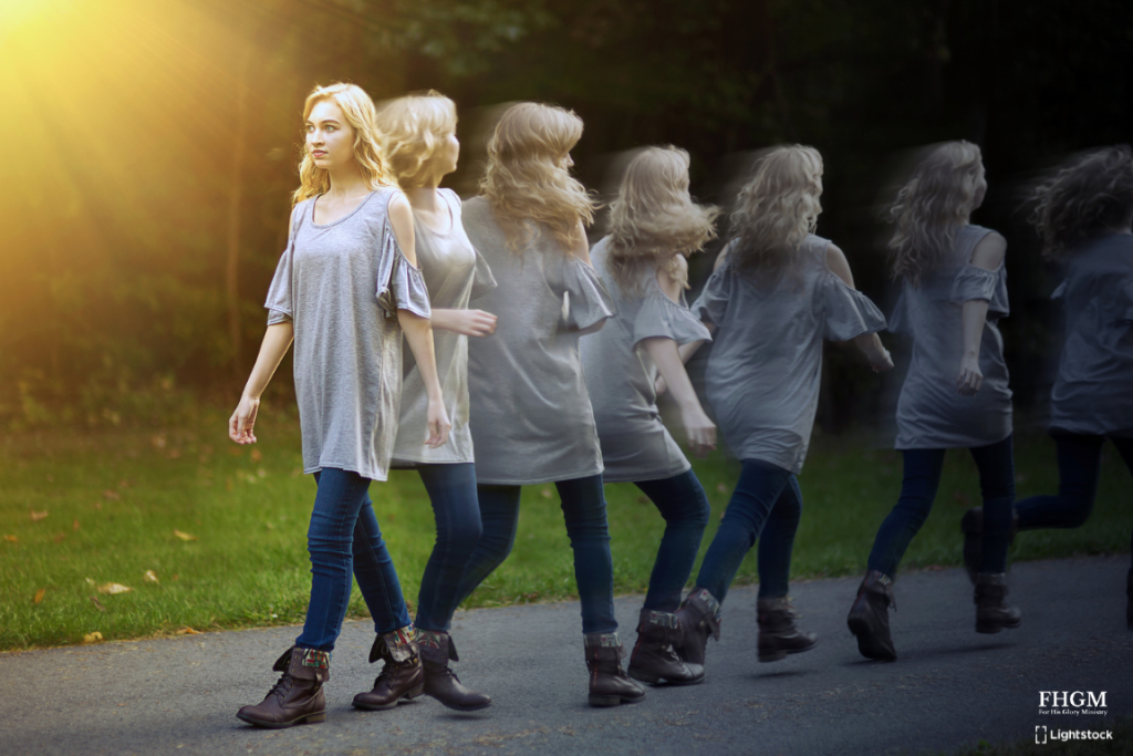 A woman walking down the street in front of trees.