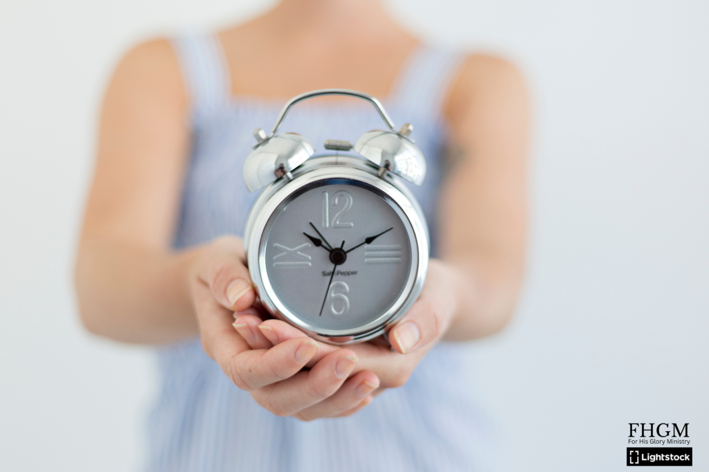 A woman holding an alarm clock in her hands.