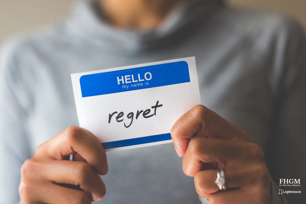 A person holding up an hello sign with regret written on it.