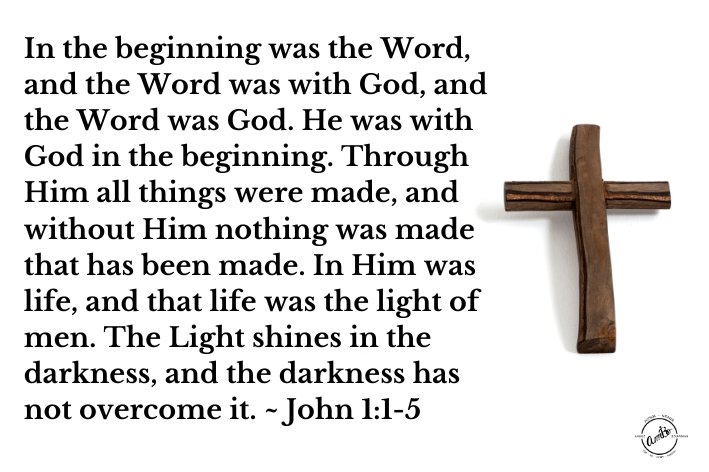 A wooden cross with the words " john 1 : 1-5 " written on it.